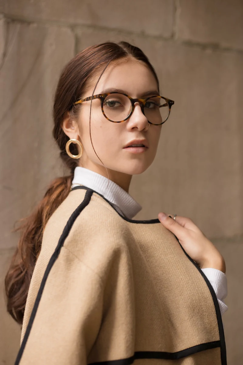 a portrait of a young woman in a stylish outfit who wears a pair of trendy turtle shell eyeglasses