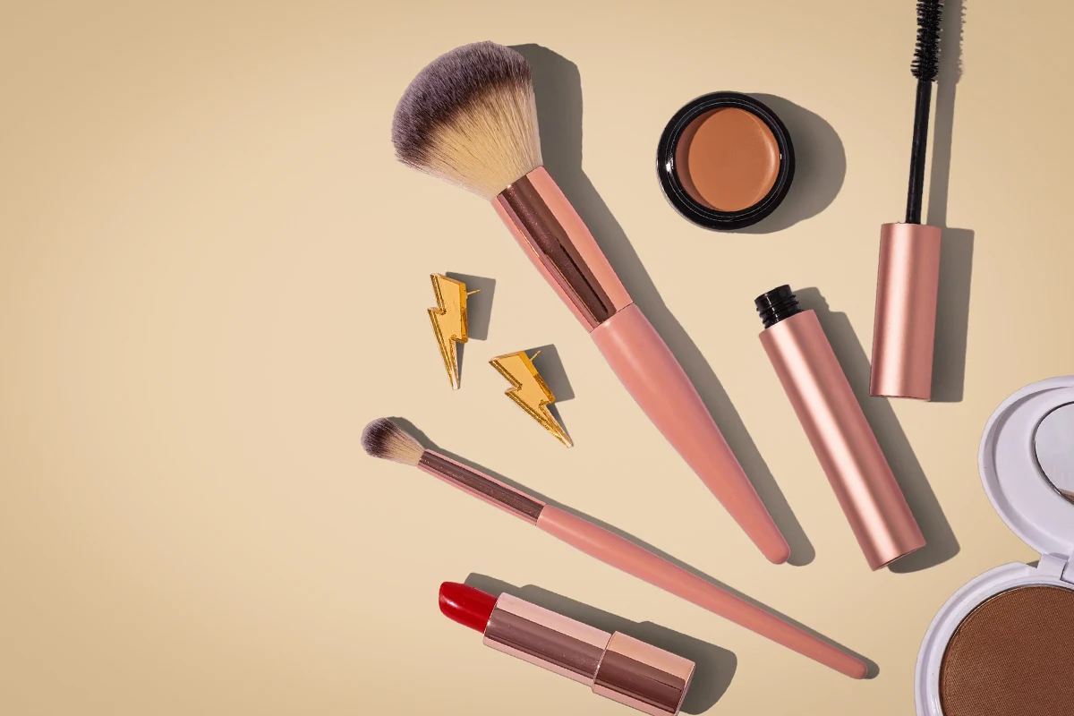brushes and makeup products scattered on a brown background