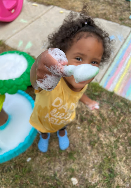 a child holding a scoop of bubbles.