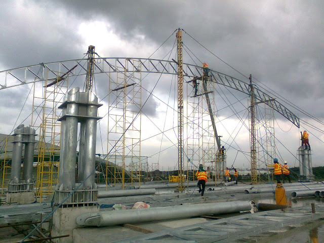 Steel erectors setting up scaffolds and jib pole with rope braces