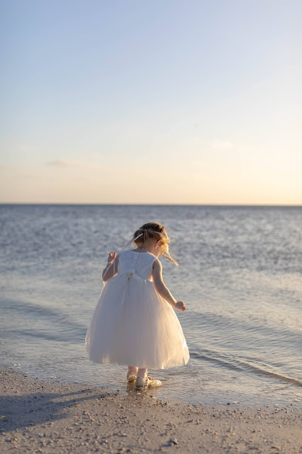 Unposed flower girl playing in the sand during sunset.