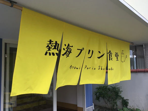 JR伊東線伊豆多賀駅より徒歩5分。熱海のプリンブームを牽引する人気店『ドライブイン 熱海プリン食堂』ののれん