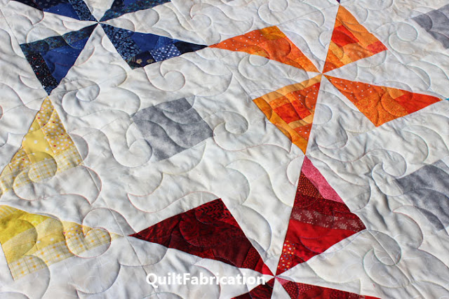 quilting with multicolored thread on a pinwheel quilt