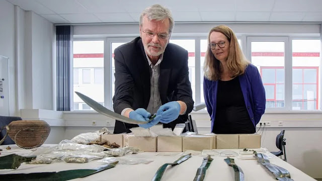 Ο αρχαιολόγος Detlef Jantzen (αριστερά) και η Bettina Martin, υπουργός Επιστήμης και Πολιτισμού, βλέπουν τα πρόσφατα αρχαιολογικά ευρήματα από τη Γερμανία, συμπεριλαμβανομένων ξίφη από την Εποχή του Χαλκού και χιλιάδες ασημένια νομίσματα. [Credit: Markus Scholz/dpa μέσω Alamy Live News]