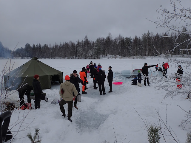 Ihmisiä jäällä avannon ympärillä, pystytettynä puolijoukkueteltta