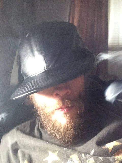 Oregonleatherboy with bushy beard wearing leather hat with smoke in mouth