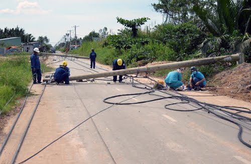 Gần chục cột điện bị xe ben kéo đổ nằm giữa đường đang được nhân viên điện lực khắc phục. Ảnh: Sơn Hòa