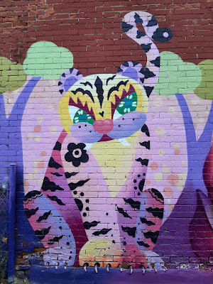 colourful mural of a cat painted on a brick wall