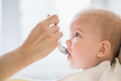 A baby being spoon fed. 