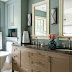 Taupe + Dusty Blue + Off White Muted-blue walls surround this bathroom with calming energy. The vanity was given a fresh coat of sandy-brown paint, which echoes the muted hue of the bathroom's walls. Warm off-white furnishings, such as the marble floor and the painted mirror frames, blend well into the room's relaxing aesthetic.