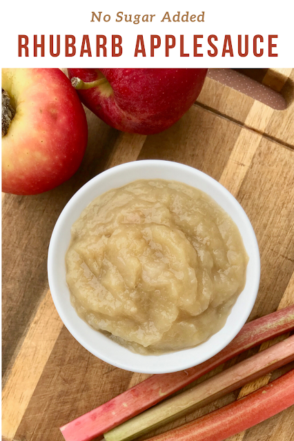 Finished bowl of rhubarb applesauce on a cutting board with rhubarb stalks and apples.