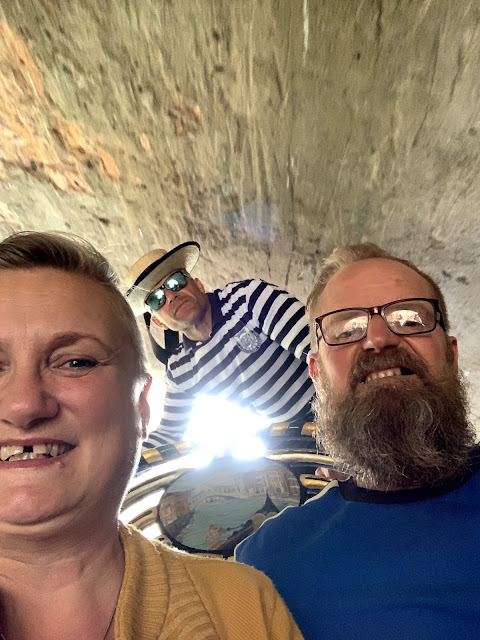 Gondalier crouches under bridge, Venice, Italy