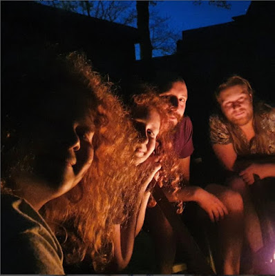 4 of my boys in the dark, sitting in the glow of a bonfire