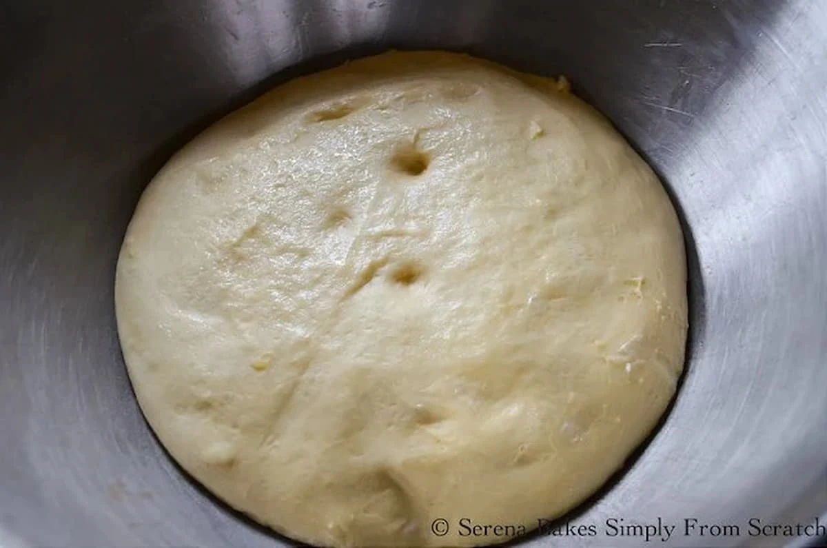 Risen Hawaiian Roll Dough in a stainless steel bowl.