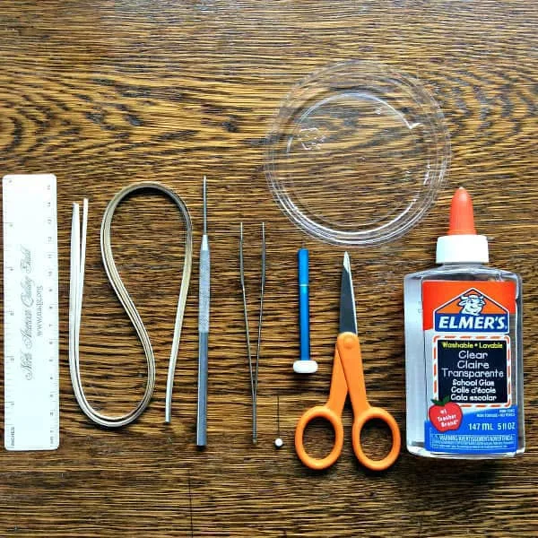 supplies for making quilled jewelry displayed on wooden table