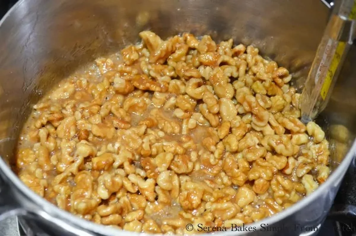 Toffee Candied Walnuts cooking in a stainless steel saucepan with candy thermometer.