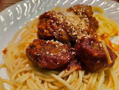 Spaghetti on a plate with meatballs in sauce on top.