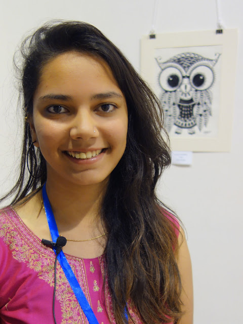 Antara Chowkase at Khula Aasmaan exhibition with her artwork in the background (www.indiaart.com)