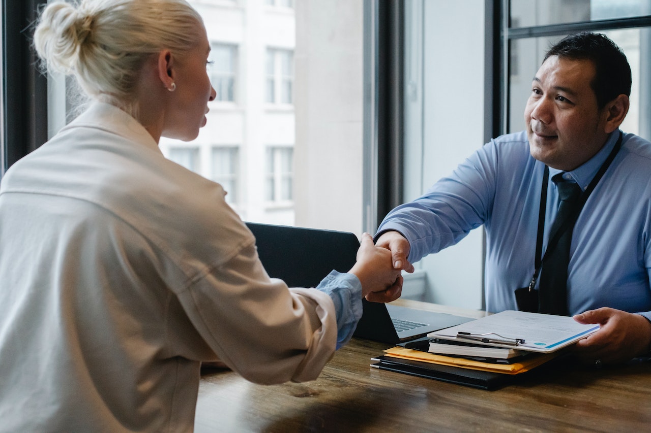 agent immobilier qui sert la main a une acheteuse apres negociation immobiliere