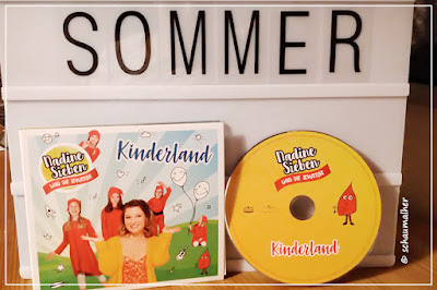 Es steht das Musikalbum vor einer Lightbox auf der mit Buchstaben das Wort Sommer geschrieben steht.