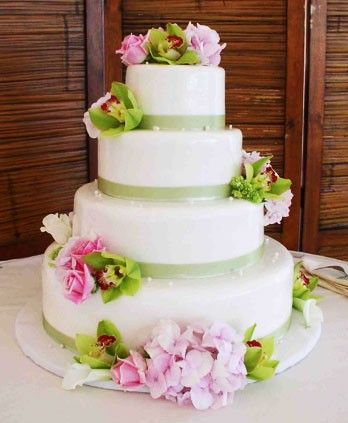Four tier white round wedding cake with green trimming green orchids and