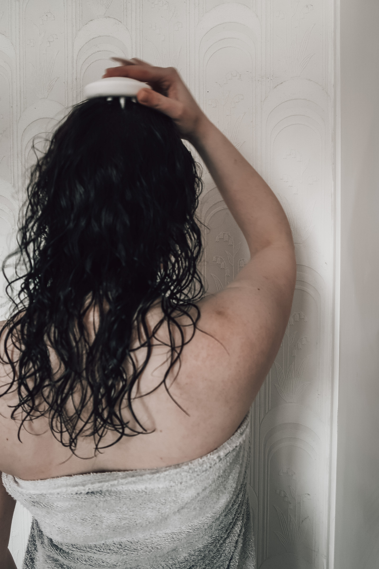 A woman using the Hello Klean Exfoliating Scalp Brush on wet hair.