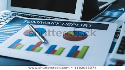 Online marketing work station with a computer, pie-chart summary reports and a silver pen.