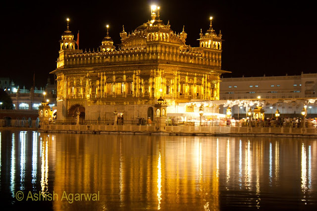 Close up view of the Golden Temple,  the sarovar surrounding it, and the causway with devotees in Amritsar