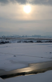 The sun breaks through, above a frozen river