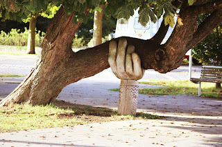 A tree being held up by a concrete support in the shape of a hand