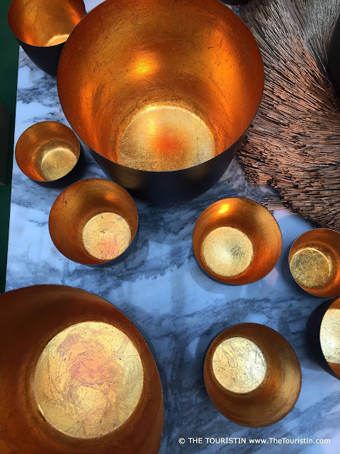 Nine different sized gold-coloured bowls on a marble table.