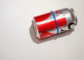 place a rubber band on the soda can