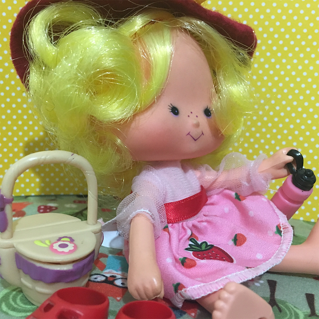 Boneca Maçãzinha pegando uma garrafinha de bebida no seu piquenique