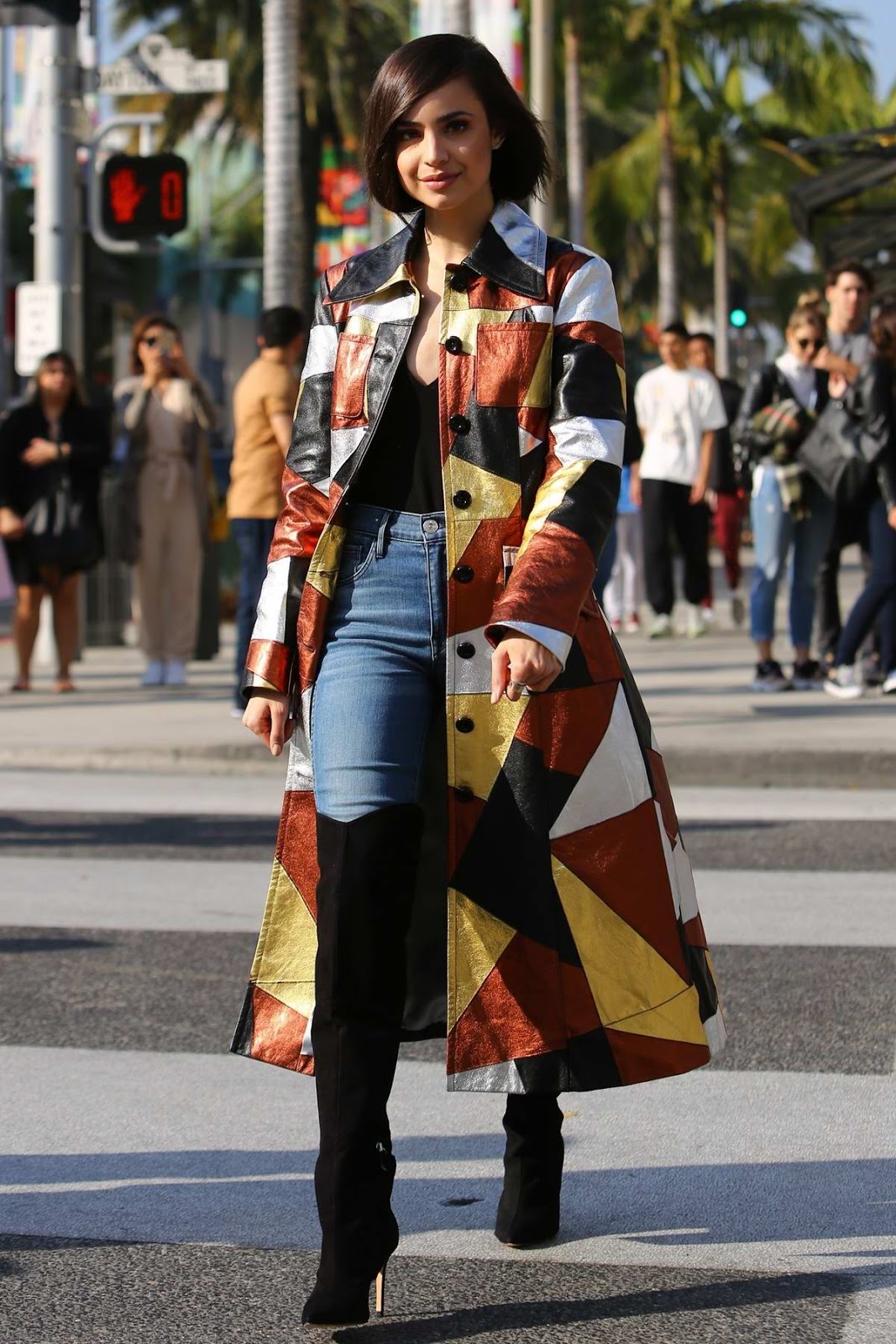Sofia Carson in a multi-colored long coat during a sidewalk interview on Rodeo Drive in Beverly Hills, California