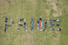 Students laying on Green spelling out PRIDE