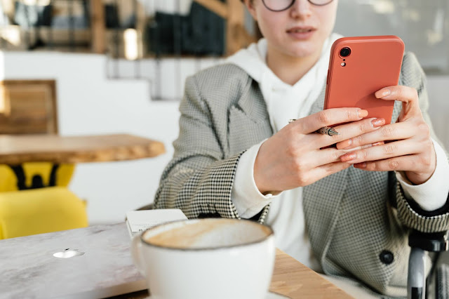 A person having coffee while browsing something on their phone.