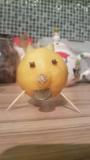 A lemon decorated to look like a pig. It has eyes made of cloves and cocktail stick legs. in it's mouth it holds a 5p coin.