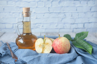 a bottle of vinegar next to two apples