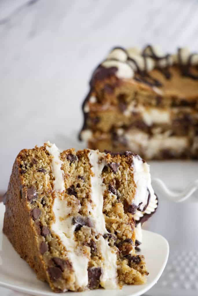 Chocolate Chip Cookie Cake with Cream Cheese Frosting - This towering chocolate chip cookie cake is made with three deep dish chocolate chip cookies that are stacked on top of each other and filled with cream cheese frosting. It is finished with a rich chocolate drizzle that makes this cake over-the-top decadent.