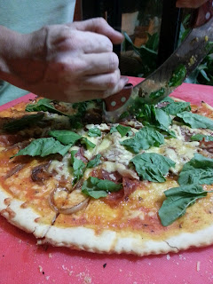 pizza de jamones con cebolla caramelizada y arugula