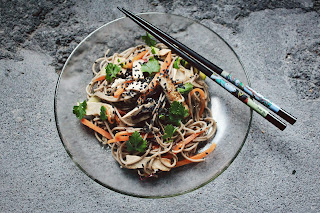 a plate of stir fry veg and noodles with chopsticks