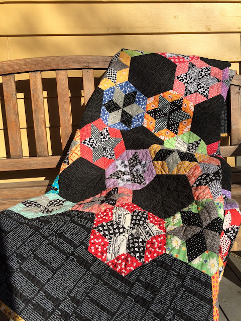 scrap quilt diamond English paper pieced blocks appliquéd onto a black background