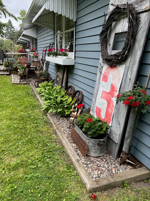 Photo of a wall of the house with junk and flowers.