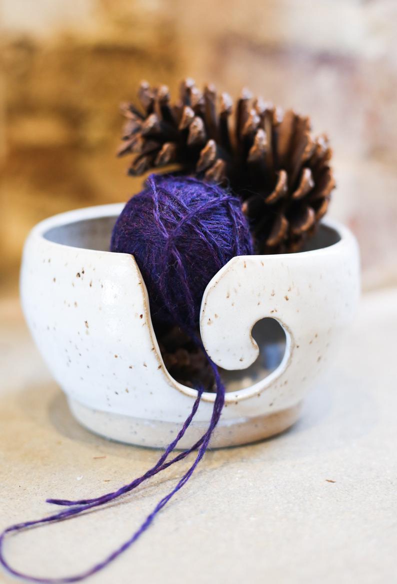 Speckled Ceramic Yarn Bowl with purple yarn and a pinecone