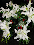 It has beautiful, white lilies, combined with a sprig of spruce and some red .