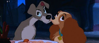 A Dama e o Vagabundo (Lady and the Tramp)  São vários os beijos eternizados no cinema. Claro que um deles acontece em um jantar com estes dois cachorrinhos. A Dama e o Vagabundo se apaixonam assim que se conhecem. Ele, em uma noite romântica, a convida para jantar no restaurante de uns amigos humanos, especializado em massas.  Vagabundo é um vira-lata de pelagem marrom com mandíbulas, pescoço e peito, bege. Focinho preto e grande, assim também os olhos e as orelhas.  Dama é uma Cocker Spaniel com pelagem caramelo, mais densa nas orelhas compridas em tom avermelhado. Dama usa uma coleira azul com plaquinha de identificação dourada.    Descrição: A Dama e o Vagabundo estão sob o luar sentados lado a lado em frente a uma travessa branca com uma farta macarronada. Ambos sugam o mesmo fio de macarrão, as bocas aproximam-se. Enamorados, olham para o alto em lados opostos.   Com esta imagem desejamos um Feliz Dia dos Namorados! 