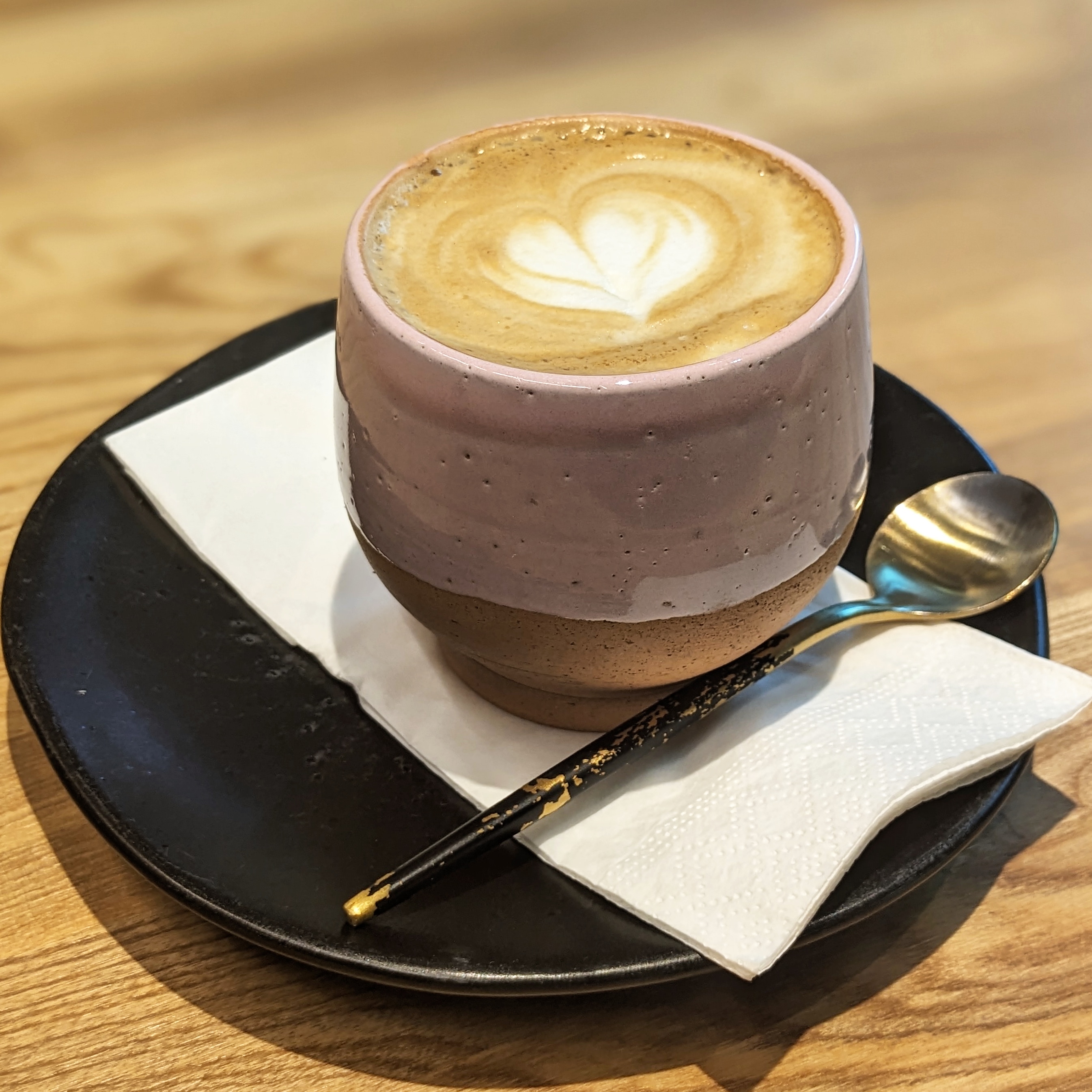 A cute pinky stubby cup of milky coffee on a saucer at red man coffee shop in tbilisi