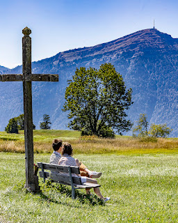 Auf dem Zugerberg geniesst ein Paar im Schatten des Kreuzes die Aussicht auf die Rigi.