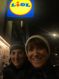 A selfie of Natalie and me under the Lidl sign in Copenhagen. The sky is dark and the sign is lit in blue and yellow.