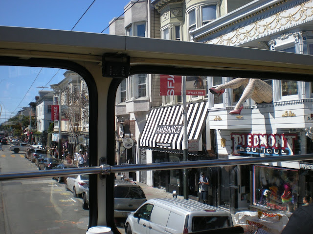 A giant statue of a woman's legs hanging out of a building's window. 